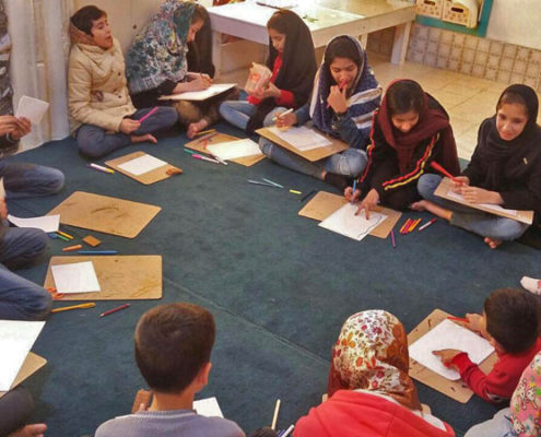 نشست بلندخوانی را، با گمانه‌زنی از روی جلد کتاب آغاز کردیم. بچه‌ها با دیدن پاکت نامه در دهان زرافه نظراتی ارائه دادند. تعدادی گفتند که داخل‌اش هدیه است. اما، یکی از بچه‌ها گفت: آن پاکت تنها یک نامه است. روی آن نوشته شده با احترام، از طرف زرافه، این‌گونه نوشتن ویژه نامه است. کتاب «با احترام، از طرف زرافه»، داستان زرافه‌ی تنهایی است که در آفریقا زندگی می‌کند و چون دوستی ندارد تصمیم می‌گیرد نامه‌ای به آن طرف افق بفرستد و دوست تازه‌ای برای خود انتخاب کند که هیچ شناختی از او ندارد. با کمک کره‌ی جغرافیایی، محل زندگی پنگوئن در قطب جنوب و زرافه در آفریقا را یافتیم. تا پیش از نشان دادن قطب جنوب، بچه‌ها فقط می‌دانستند که پنگوئن‌ها در یخ و برف زندگی می‌کنند. در ادامه، پرسش‌ و پاسخ‌هایی مطرح شد. به طور مثال، افق کجاست؟ تعدادی گفتند: یک جای دور، و یا آب دریا چرا به هنگام غروب نارنجی دیده می‌شود و بسیار پرسش دیگر. در فعالیت پس از بلندخوانی، بچه‌ها نامه‌ای به دوست خیالی‌شان نوشتند و ویژگی‌های خود را توصیف کردند. محل اجرا: آوای ماندگار مربی: فرشته آزاد دهقان